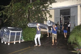 Các công nhân di dời vải ra khỏi kho hàng đang bị cháy. (Ảnh: TTXVN phát) 