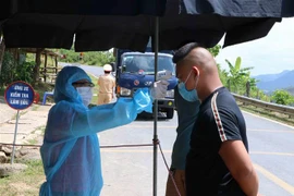 Kiểm tra thân nhiệt người dân vào tỉnh Lai Châu tại chốt kiểm soát dịch bệnh COVID-19 Lai Hà trên quốc lộ 12 giáp ranh với thị xã Mường Lay, tỉnh Điện Biên. (Ảnh: Nguyễn Oanh/TTXVN) 