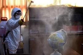 Nhân viên hội Chữ thập Đỏ phun thuốc khử trùng tại trường học ở Jakarta, Indonesia ngày 20/3/2020, nhằm ngăn chặn sự lây lan của COVID-19. (Nguồn: THX/TTXVN) 