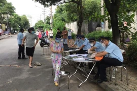 Lực lượng hải quan tỉnh Bình Dương chi viện hỗ trợ thành phố Dĩ An để kịp thời cấp phát tiền hỗ trợ cho dân trong vùng khóa chặt. (Ảnh: TTXVN phát) 