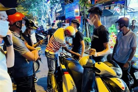 Đêm 27/8, tại đường Trần Nhật Duật (đoạn lối lên cầu Long Biên), tổ công tác Y1/141 đã phát và xử lý hai thanh niên không đội mũ bảo hiểm, chở theo bình bóng cười kèm nhiều vỏ bóng. (Ảnh: Phạm Kiên/TTXVN) 