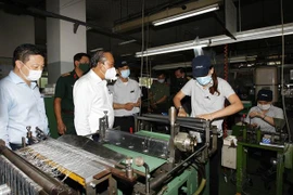 Phó Thủ tướng thường trực Chính phủ Trương Hòa Bình kiểm tra phòng, chống dịch bệnh tại Công ty trách nhiệm hữu hạn Kim may Organ. (Ảnh: Thanh Vũ/TTXVN) 