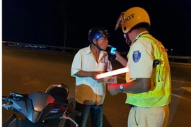 Cảnh sát giao thông kiểm tra nồng độ cồn. (Ảnh: Xuân Triệu/TTXVN) 