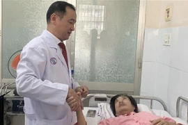 Tiến sỹ, bác sỹ Ngô Đức Hiệp, Trưởng Khoa Phỏng-Phẫu thuật tạo hình, động viên người bị nạn. (Ảnh: Đinh Hằng/TTXVN)