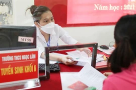 Ban tuyển sinh trường THCS Ngọc Lâm, quận Long Biên, Hà Nội hỗ trợ phụ huynh kiểm tra hồ sơ, giải đáp thắc mắc trong cách thức tuyển sinh trực tuyến cho con em vào lớp 6. (Ảnh: Thanh Tùng/TTXVN) 