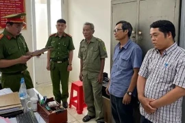 Công an đọc lệnh khởi tố, bắt tạm giam bị can Nguyễn Đức Khuê và Lê Ngọc Muôn. (Ảnh: TTXVN phát)