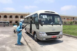 Thực hiện khử khuẩn xe chở các công dân sau khi hoàn thành nhiệm vụ. (Ảnh: Đức Phương/TTXVN)