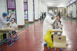 Nhân viên y tế lấy mẫu xét nghiệm COVID-19 cho học sinh tại Vũ Hán, Trung Quốc ngày 14/5/2020. (Nguồn: AFP/TTXVN) 