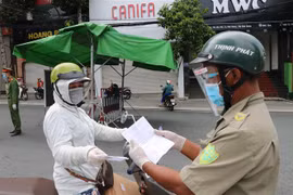 Một người phụ nữ đi chợ trình giấy có giấy tiêm đủ vaccine cho lực lượng kiểm tra trên đường Yersin, thành phố Thủ Dầu Một. (Ảnh: Chí Tưởng/TTXVN) 