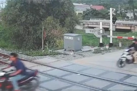 Tại thời điểm vụ tai nạn xảy ra, rất nhiều người cố vượt qua gác chắn đường sắt. (Ảnh: TTXVN phát) 