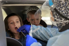 Nhân viên y tế Israel lấy mẫu xét nghiệm COVID-19 cho trẻ em tại Jerusalem. (Ảnh: AFP/TTXVN) 