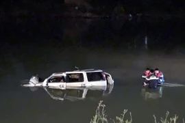 Lực lượng cứu hộ trục vớt chiếc xe ôtô 7 chỗ cùng các thi thể nạn nhân trong đêm. (Nguồn: TTXVN phát) 