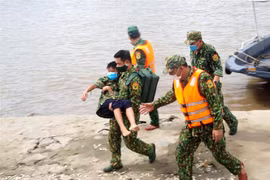 Lực lượng Quân y Biên phòng đưa các nạn nhân vào bờ và kiểm tra sức khỏe cho các nạn nhân. (Ảnh: TTXVN) 