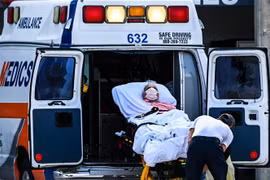 Nhân viên y tế chuyển bệnh nhân COVID-19 tới bệnh viện tại Coral Gables, gần Miami, Mỹ. (Ảnh: AFP/TTXVN) 
