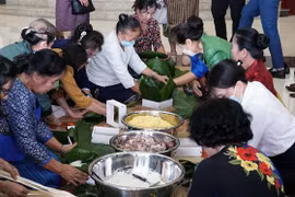 Cựu lưu học sinh Lào tham gia gói bánh chưng. (Ảnh: Phạm Kiên/TTXVN) 
