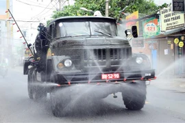 Lực lượng phòng hóa quân đội triển khai các phương tiện kỹ thuật tiến hành phun khử khuẩn diện rộng trên địa bàn quận Gò Vấp. (Nguồn: TTXVN phát) 