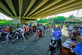 Người dân khai báo thông tin tại chốt kiểm soát dưới cầu Vàm Cống, quận Thốt Nốt. (Ảnh: Thanh Liêm/TTXVN) 