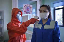 Nhân viên y tế kiểm tra thân nhiệt trước khi vào một nhà máy ở Bình Nhưỡng, Triều Tiên, ngày 16/6/2022. (Ảnh: AFP/TTXVN) 