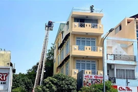 Cảnh sát chữa cháy tiếp cận từ nóc nhà để giải cứu 2 nạn nhân. (Nguồn: TTXVN phát) 