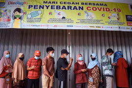 Người dân đeo khẩu trang xếp hàng mua thực phẩm tại Bandung, Indonesia, ngày 18/2/2022. (Ảnh: AFP/TTXVN) 