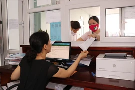 Người dân giao dịch tại quầy Bảo hiểm xã hội tỉnh Bắc Ninh. (Ảnh: Đinh Văn Nhiều/TTXVN) 