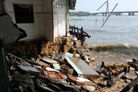 Một ngôi nhà của người dân bị trôi một phần theo những cơn sóng lớn. (Ảnh: Đặng Tuấn/TTXVN) 