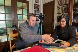 Ông Michel Strachinescu chia sẻ với phóng viên những bức ảnh kỷ niệm khi ông còn là lái xe cho phái đoàn Việt Nam. (Ảnh: Thu Hà/TTXVN)