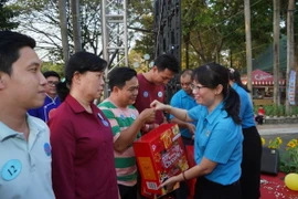 Bà Trần Thị Diệu Thúy, Chủ tịch Liên đoàn Lao động Thành phố Hồ Chí Minh, tăng quà cho công nhân lao động. (Ảnh: Thanh Vũ/TTXVN)