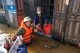 Lực lượng công an huyện Lệ Thủy lội nước, đưa hàng cứu trợ đến những gia đình bị cô lập trong nước lũ. (Ảnh: Thành Đạt/TTXVN) 