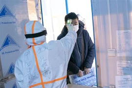 Nhân viên y tế kiểm tra thân nhiệt cho bệnh nhân nhiễm virus COVID-19 tại một bệnh viện dã chiến ở Vũ Hán, Trung Quốc ngày 5/2/2020. (Nguồn: THX/TTXVN) 