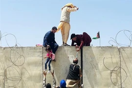 Người dân Afghanistan trèo qua bức tường rào để vào sân bay quốc tế ở Kabul với hy vọng được sơ tán khi Taliban tuyên bố giành quyền kiểm soát đất nước, ngày 16/8/2021. (Ảnh: Getty Images/TTXVN) 