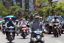 Người dân đi trên đường phải bịt kín để bảo vệ cơ thể dưới trời nắng. (Ảnh: Phan Tuấn Anh/TTXVN) 