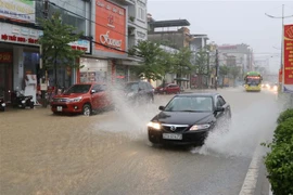 Phương tiện tham gia giao thông qua các tuyến đường ngập úng trên địa bàn thành phố Điện Biên Phủ, tỉnh Điện Biên. (Ảnh: Xuân Tiến/TTXVN) 