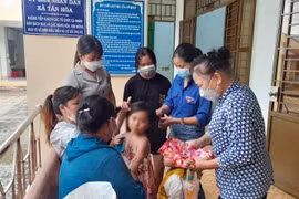 Các hội, đoàn thể của huyện và xã Tân Hòa sửa soạn cho bé L.Y.D trước khi bé về quê cùng cha ruột. (Ảnh: Đậu Tất Thành/TTXVN) 