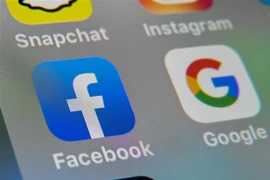 Biểu tượng của Facebook và Google trên màn hình máy tính bảng. (Nguồn: AFP/TTXVN) 
