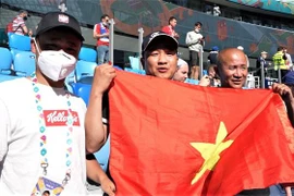 Anh Hoàng Văn Phú (giữa) và anh Nguyễn Đức Vượng (phải) đến từ Vladivostok, cách St. Petersburg 7 múi giờ, để cổ vũ cho tuyển Nga. (Ảnh: Duy Trinh/TTXVN) 