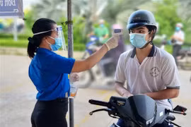 Tình nguyện viên đo thân nhiệt cho người dân. (Ảnh: Hữu Chí/TTXVN) 