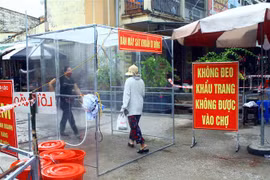 Người dân phải qua buồng khử khuẩn tự động trước khi vào mua hàng tại một chợ ở tỉnh Nghệ An. (Ảnh: Tá Chuyên/TTXVN) 