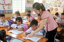Giáo viên trường Tiểu học Nam Tiến, huyện Nam Trực (Nam Định) hướng dẫn học sinh làm bài tập. (Ảnh: Nguyễn Lành/TTXVN) 