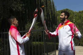 Vận động viên trượt tuyết người Hy Lạp Ioannis Antoniou (phải) truyền ngọn đuốc Olympic của Thế vận hội mùa Đông Bắc Kinh 2022 cho cựu vận động viên trượt băng tốc độ quãng đường ngắn người Trung Quốc Li Jiajun, ở Olympia (Hy Lạp), ngày 18/10/2021. (Ảnh: 