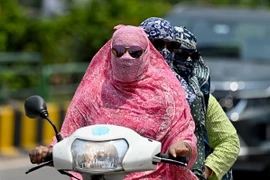 Người dân trùm kín tránh nắng nóng khi di chuyển tại Raipur, Ấn Độ ngày 15/4/2024. (Ảnh: AFP/TTXVN)