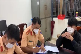 Cảnh sát giao thông lập biên bản thanh thiếu niên vi phạm. (Ảnh: Đậu Tất Thành/TTXVN) 