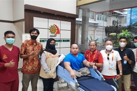 Bác sỹ chuyên khoa II Lương Văn Sinh (thứ tư, từ phải sang), Tổ trưởng Tổ y tế thuộc Đoàn thể thao người khuyết tật Việt Nam, hỗ trợ khám vết thương cho đô cử Nguyễn Bình An tại bệnh viện. (Ảnh: TTXVN phát) 
