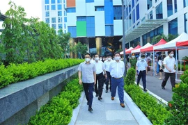 Phó Thủ tướng Chính phủ Vũ Đức Đam, Trưởng Ban chỉ đạo Quốc gia phòng, chống COVID-19 kiểm tra tại điểm tiêm vắc xin 04 dây chuyền tại trụ sở Tập đoàn FPT. (Ảnh: Minh Đức/TTXVN) 