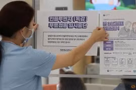 Một nhân viên y tế dán thông báo tạm dừng chương trình tiêm chủng cúm trước cổng một bệnh viện ở Sejong, Hàn Quốc, ngày 22/9/2020. (Ảnh: Reuters / Yonhap) 
