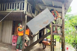 Cán bộ chiến sỹ Đồn Biên phòng Làng Mô, Bộ đội Biên phòng Quảng Bình giúp người dân di dời đồ đạc, tài sản lên chỗ an toàn phòng tránh mưa lũ. (Ảnh: TTXVN phát) 