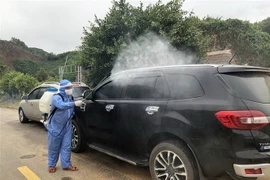 Phun thuốc khử trùng phương tiện tại chốt kiểm soát phòng, dịch bệnh COVID-19 trên đường Hồ Chí Minh qua địa bàn Quảng Nam. (Ảnh: Trần Tĩnh/TTXVN) 