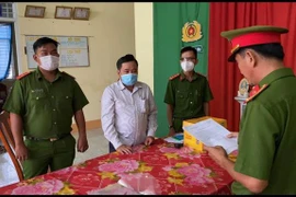 Cơ quan Cảnh sát điều tra Công an huyện Phú Tân (An Giang) đọc quyết định khởi tố vụ án, khởi tố bị can và bắt tạm giam đối với bị can Nguyễn Phước Linh (áo trắng). (Ảnh: TTXVN phát) 