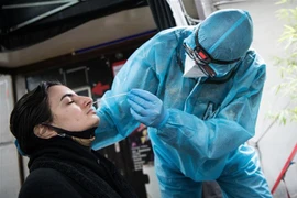 Nhân viên y tế lấy mẫu xét nghiệm COVID-19 cho người dân tại Berlin, Đức. (Ảnh: AFP/TTXVN) 