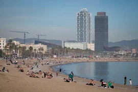 Người dân tắm mát trên bãi biển ở Barcelona, Tây Ban Nha. (Ảnh: AFP/TTXVN)